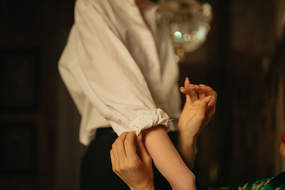 Close-up of a woman adjusting the sleeve of a white shirt, showcasing fashion and careful tailoring.