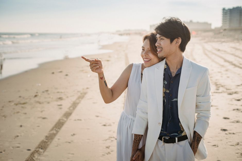 A happy couple in love enjoying a sunny day at the beach, embracing and smiling.