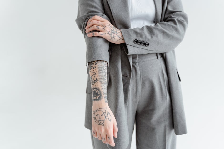 Close-up of a tattooed arm in a gray business suit, showcasing detailed ink designs.