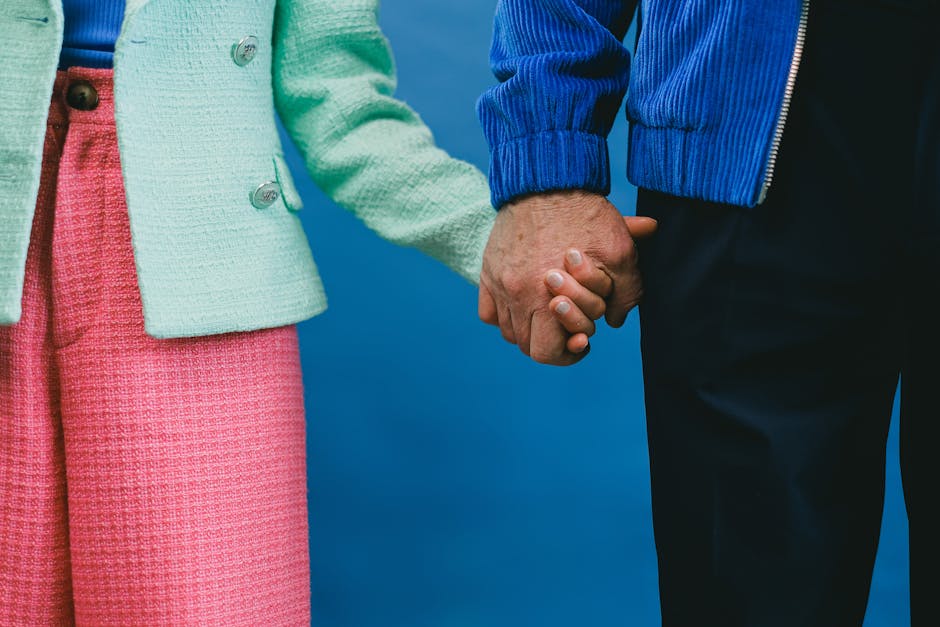 A couple holding hands, dressed in vibrant blue and pink clothing, symbolizing unity and love.