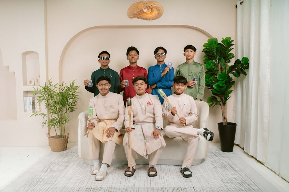 Group of young men in stylish traditional attire posing indoors with props in a modern setting.