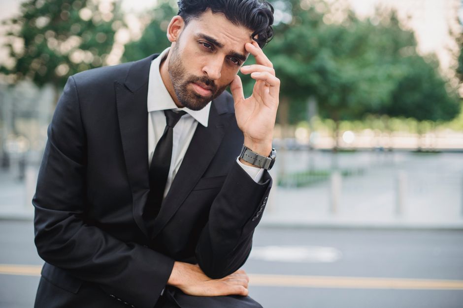 A thoughtful businessman in a suit outdoors, contemplating decisions.