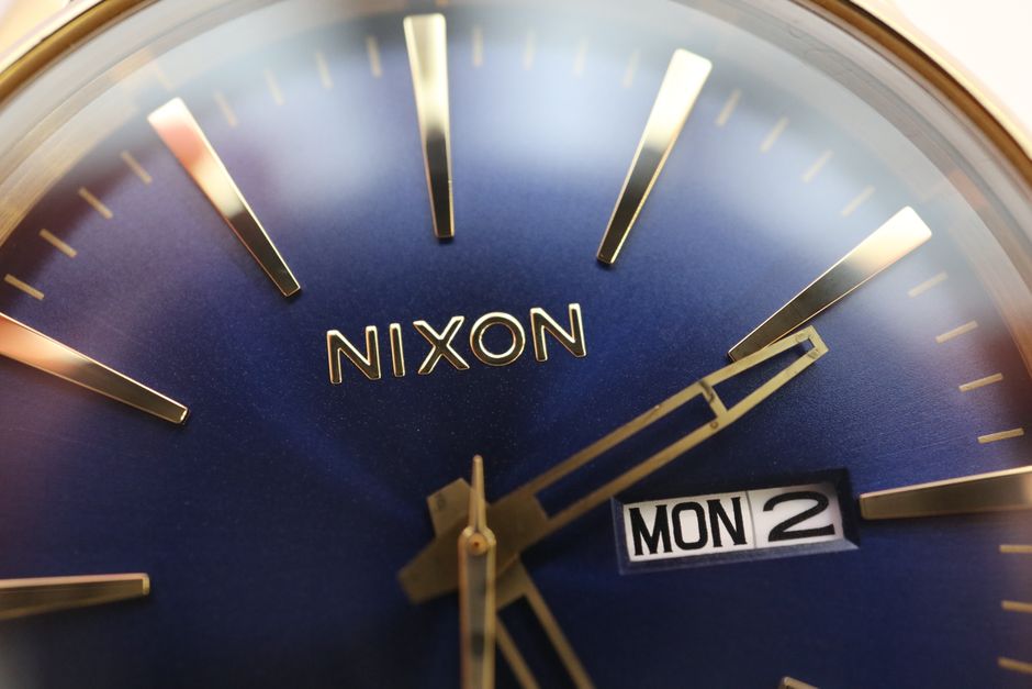 Detailed close-up of a Nixon watch dial showcasing time and date with a sleek blue face.