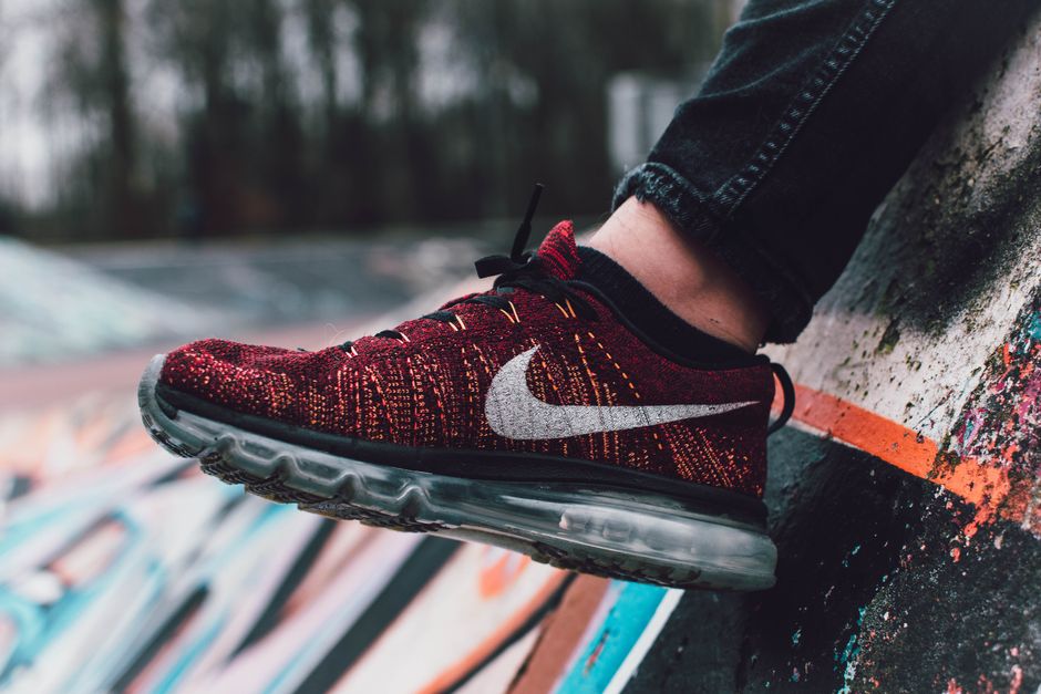 Vibrant red sneaker displayed against a dynamic graffiti wall in outdoor setting.