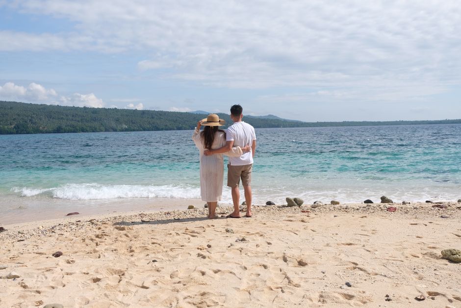 A couple embracing on a beautiful Philippine beach overlooking a tranquil sea.