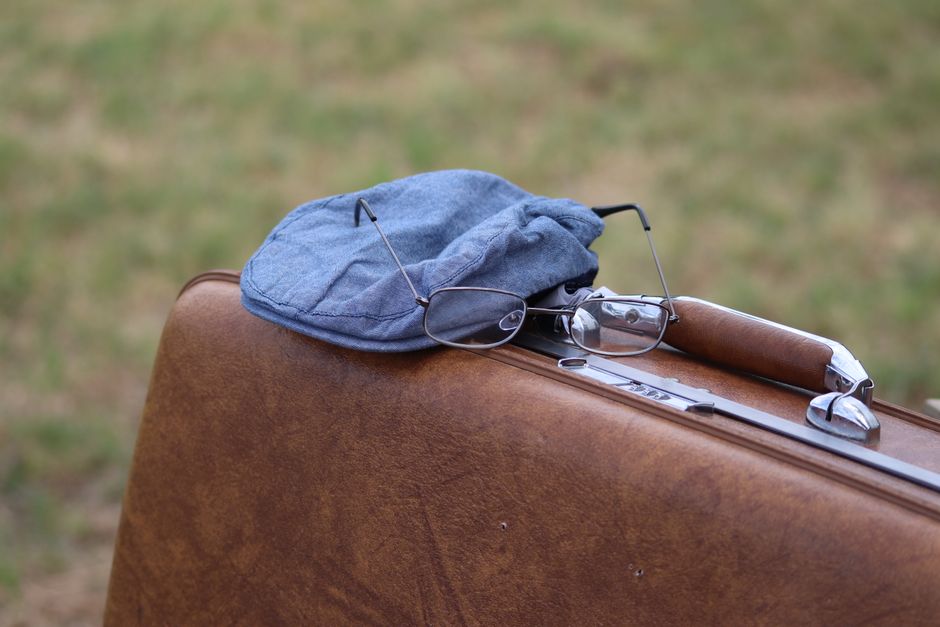 A classic scene featuring a vintage suitcase with a hat and glasses, evoking travel memories.