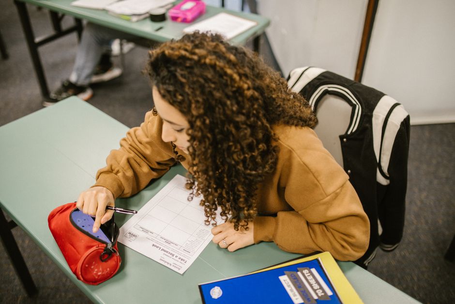 A college student studying for an exam with a smartphone hidden in a pencil case.