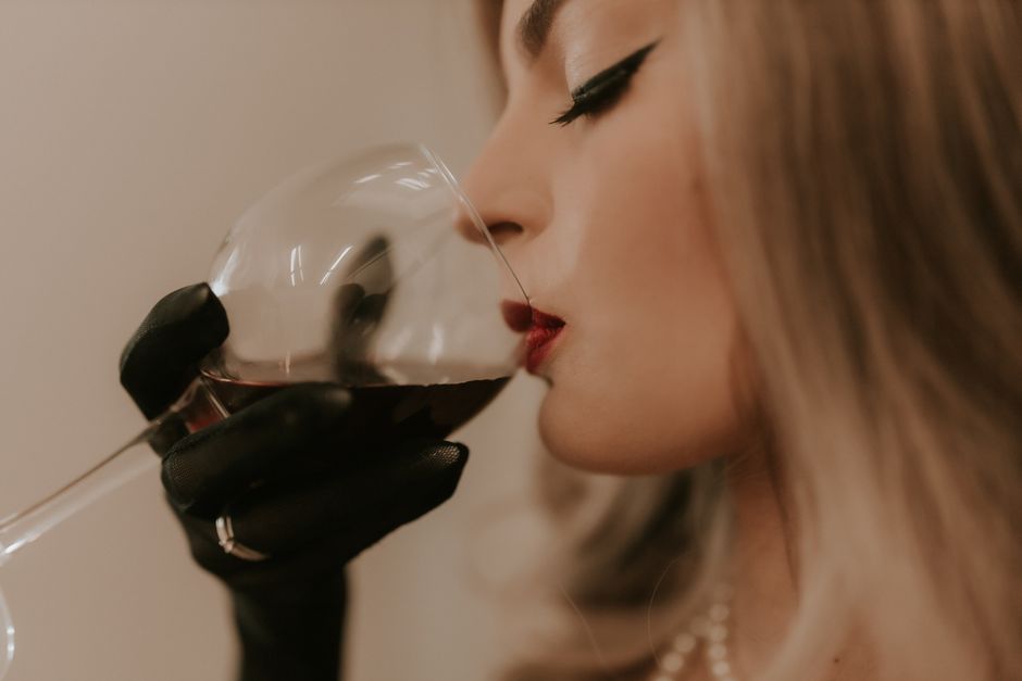 An elegant woman sipping a glass of red wine, showcasing glamour and style.