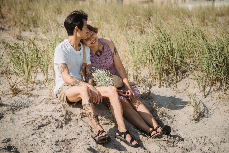 A happy couple sitting on the beach, enjoying a romantic moment surrounded by nature.