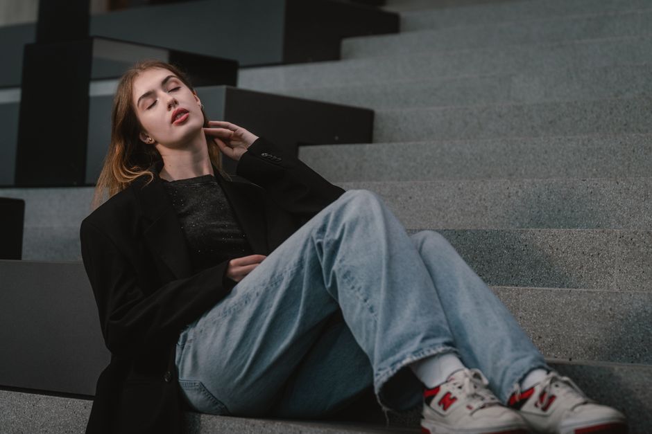 Stylish young woman in urban setting, relaxed on modern steps in Vienna.