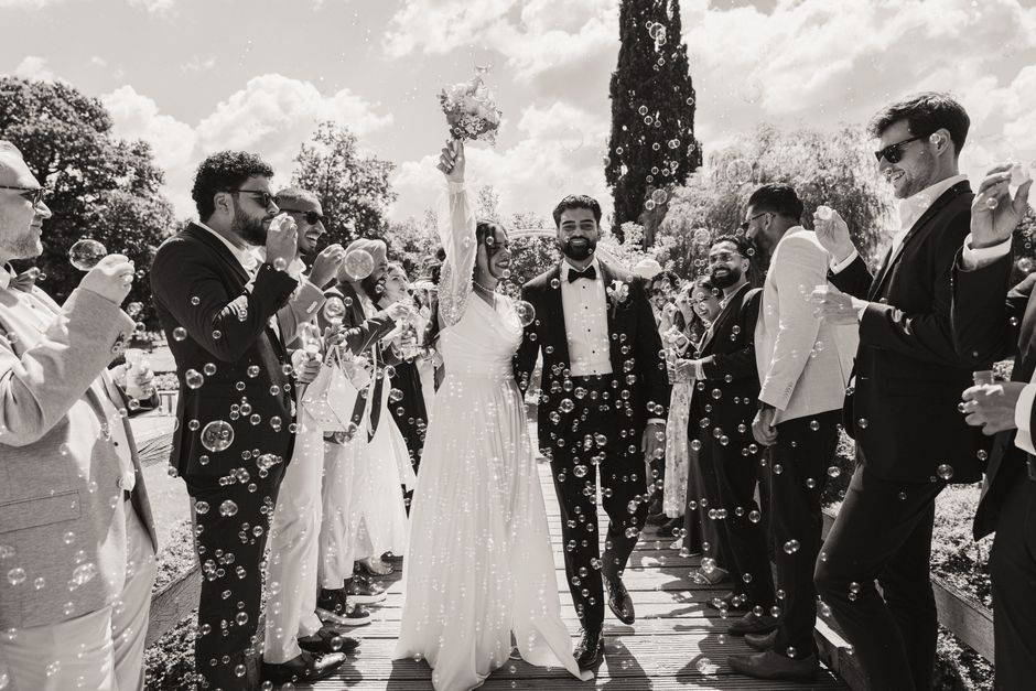 Bride and groom walk through a bubble tunnel created by guests at an outdoor wedding in Hamburg.