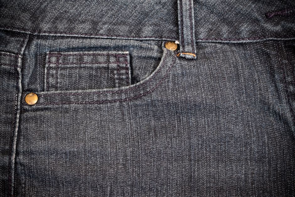 Detailed view of blue denim jeans showcasing stitching and copper rivets.