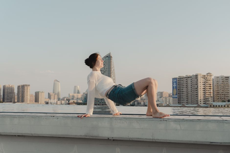 Person enjoying a rooftop view of modern city buildings under a clear sky.