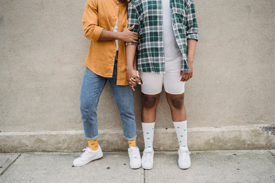 A diverse couple holding hands in casual attire, showcasing fashion and unity.