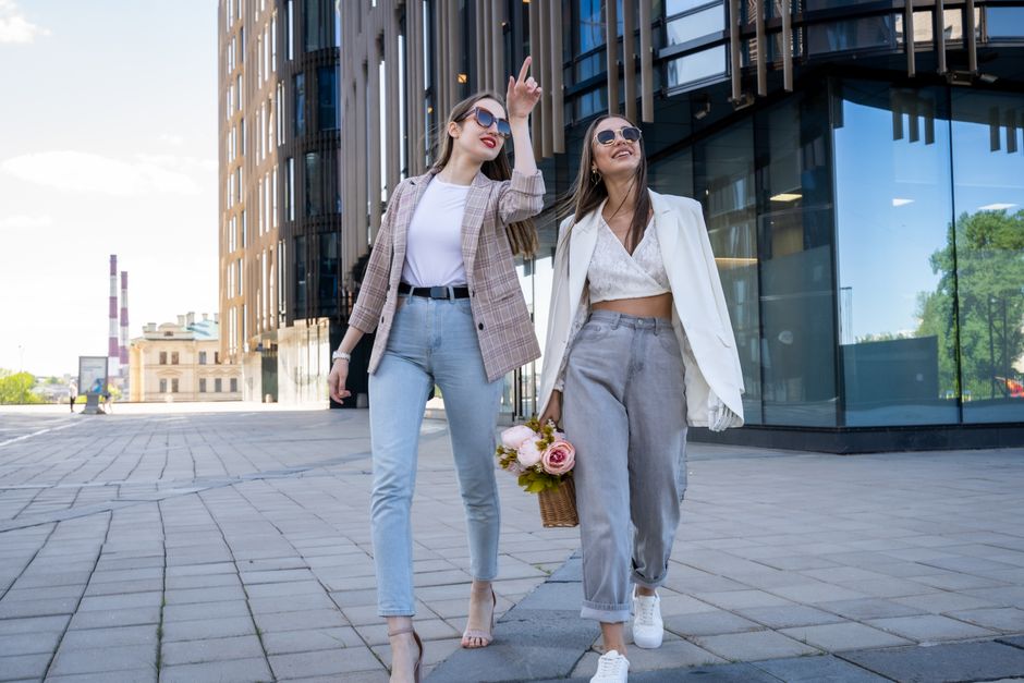 Two stylish women in sunglasses walking outdoors, embracing fashion trends.