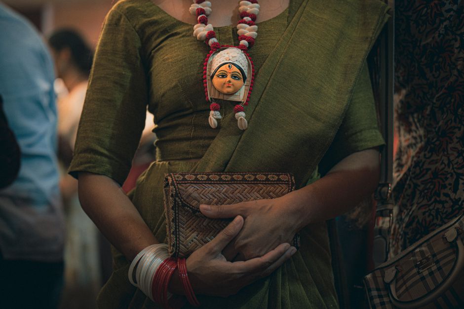 A person wearing traditional Indian saree with a Durga pendant, showcasing cultural heritage.