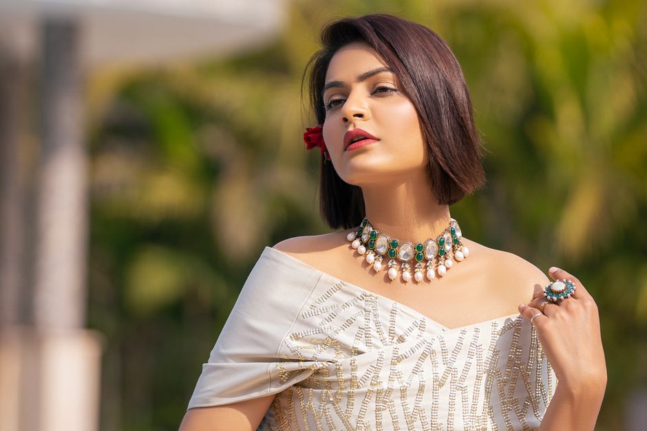 Striking outdoor portrait of a woman with jewelry and a stylish outfit.