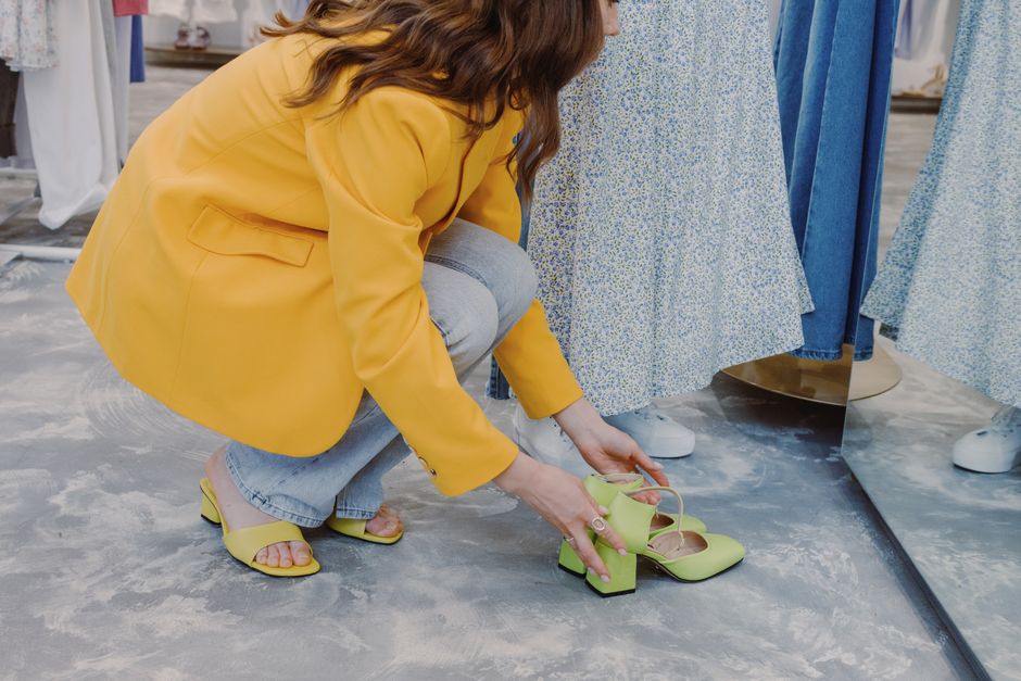 Stylish woman trying on vibrant shoes in a modern department store.