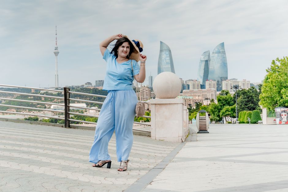 Woman in blue outfit posing outdoors in Baku, Azerbaijan with iconic Flame Towers skyline in view.