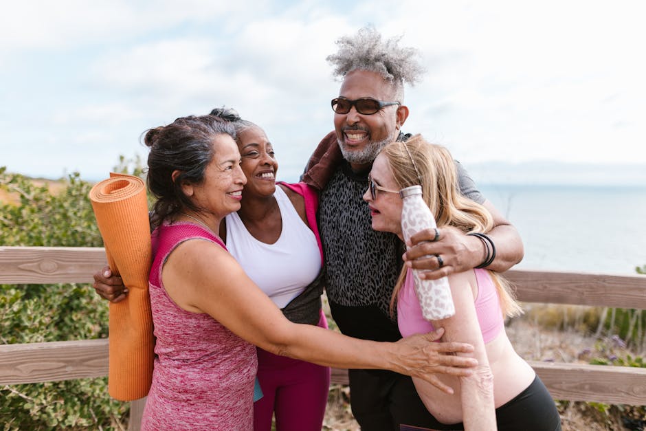 Happy senior friends embracing after a yoga session by the beach, enjoying the outdoors together.